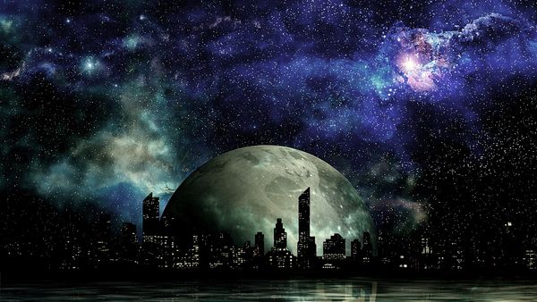 Planet rise behind a night time urban silhouette.